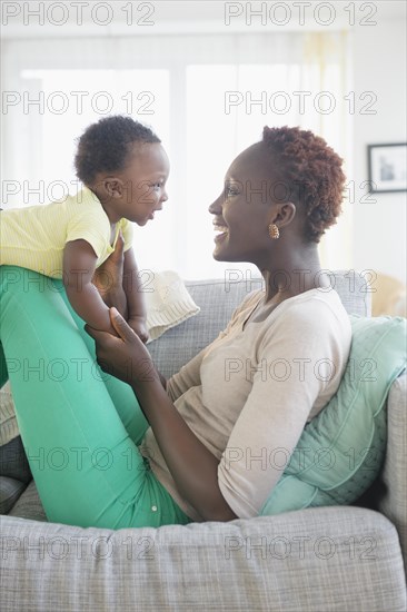 Black mother and son playing on sofa