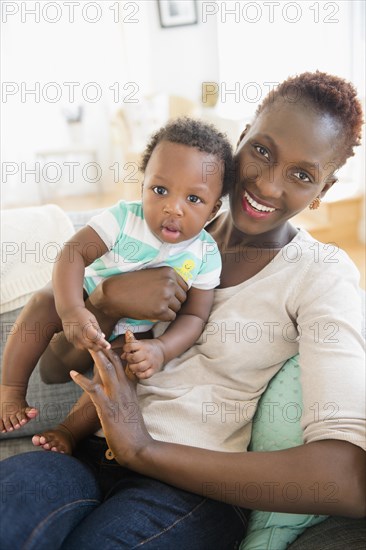 Black mother and son playing on sofa