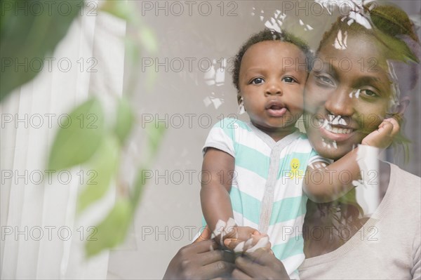 Black mother and son looking out window