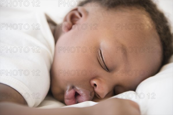 Close up of Black baby boy sleeping on bed