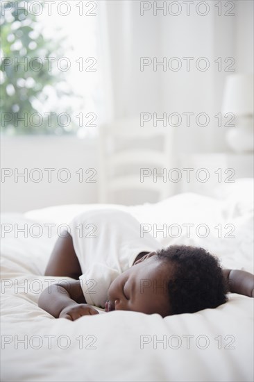 Black baby sleeping on bed