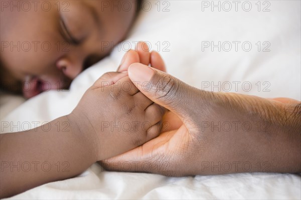 Close up of Black mother holding hand of sleeping baby