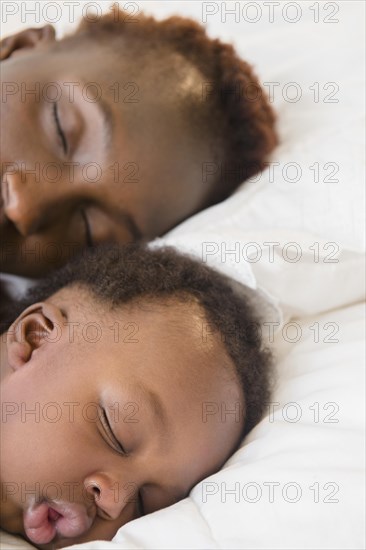 Black mother and son sleeping on bed