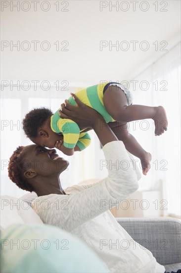 Black mother playing with baby boy on sofa