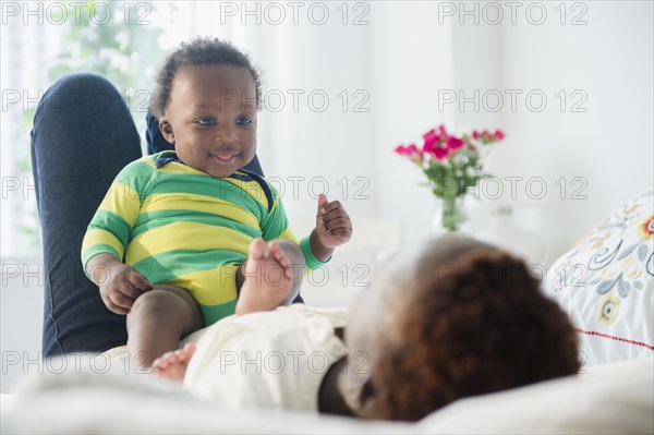 Black mother playing with baby boy on bed