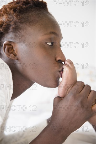 Close up of Black mother kissing feet of baby boy