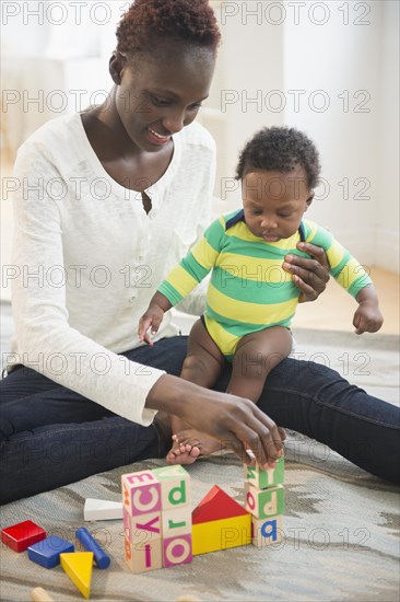 Black mother playing with baby boy in living room