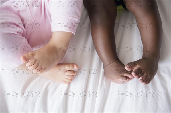 Close up of legs of babies on bed
