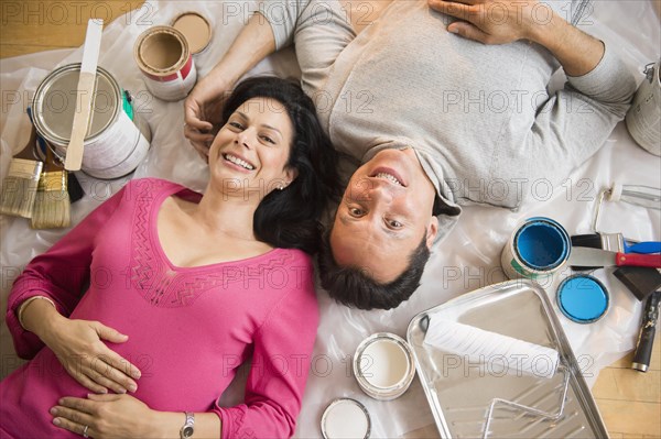 Overhead view of couple laying on drop cloth during remodeling