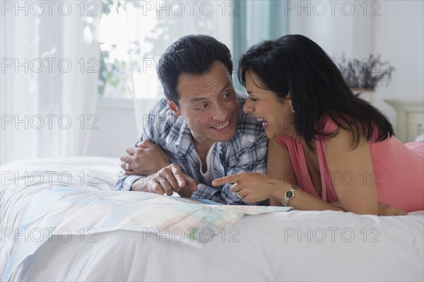 Couple reading map on bed