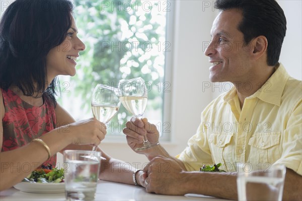 Couple toasting each other with white wine in restaurant