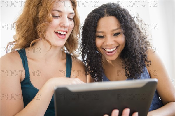 Women using digital tablet on sofa