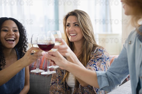 Women toasting each other with wine in living room