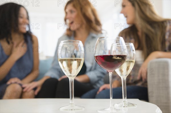 Women drinking wine and talking on sofa in living room