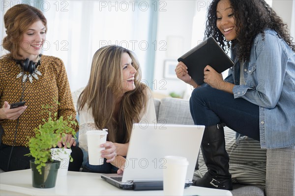 Women using digital tablet and laptop in living room