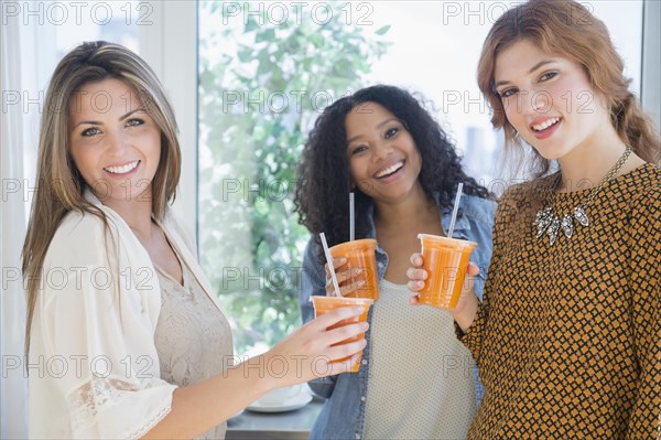 Women drinking healthy juice near window