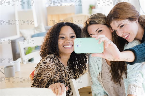 Women taking cell phone photograph in dining room