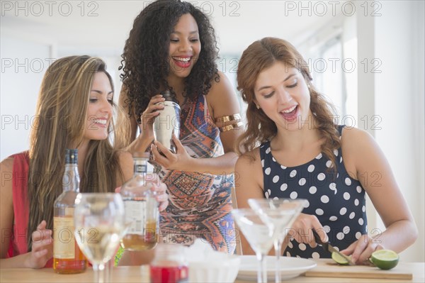 Women making cocktails in kitchen