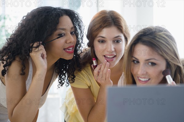 Women applying makeup in mirror