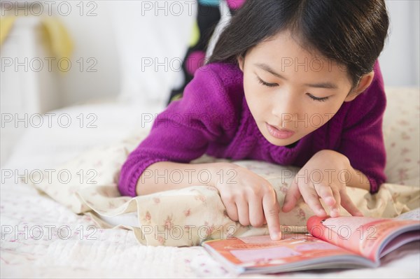 Close up of Vietnamese girl reading book on bed
