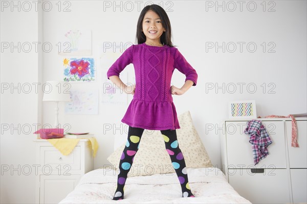 Smiling Vietnamese girl standing on bed