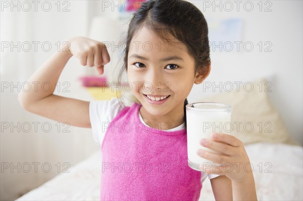 Vietnamese girl flexing muscles with glass of milk