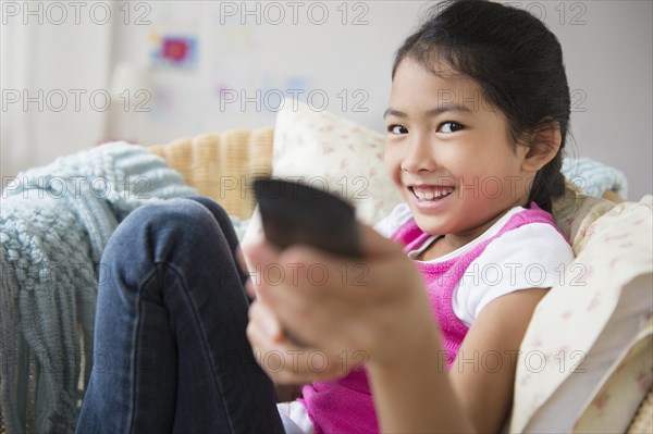 Vietnamese girl watching television in armchair