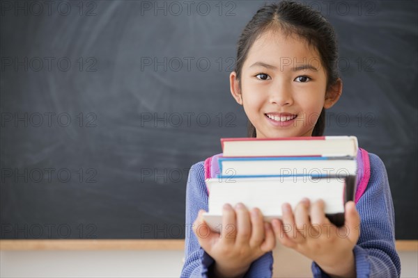 Vietnamese student carrying textbooks in classroom
