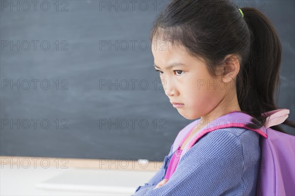 Frowning Vietnamese girl standing in classroom