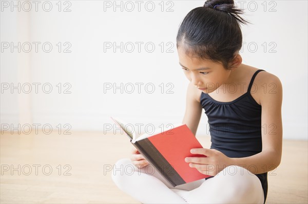 Vietnamese ballet dancer reading book in studio