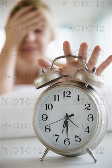 Caucasian woman shutting off alarm clock