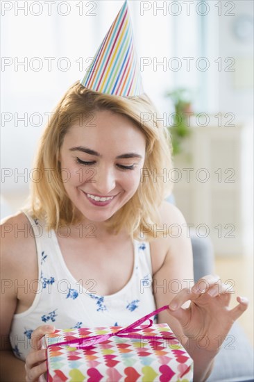 Caucasian woman unwrapping birthday present at party