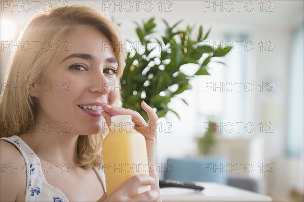 Caucasian woman drinking juice in living room