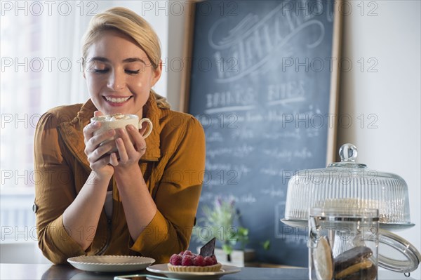 Caucasian woman smelling cup of coffee in cafe