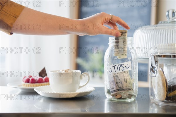 Caucasian woman putting money in tip jar