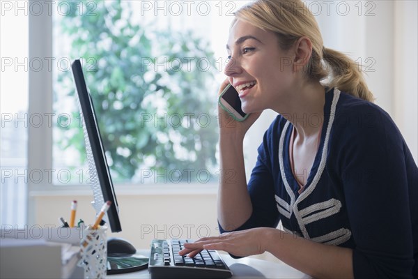 Caucasian businesswoman multi-tasking at desk