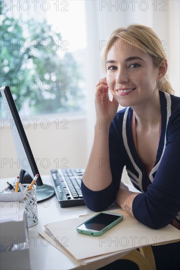 Caucasian businesswoman smiling at desk