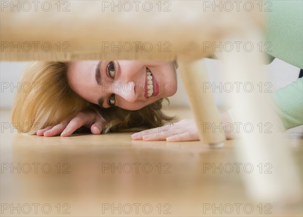 Caucasian woman peeking under chair