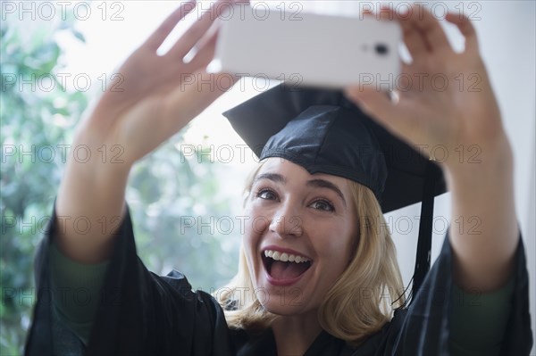 Caucasian student taking cell phone photograph at graduation