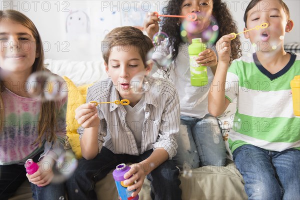 Children blowing bubbles on sofa