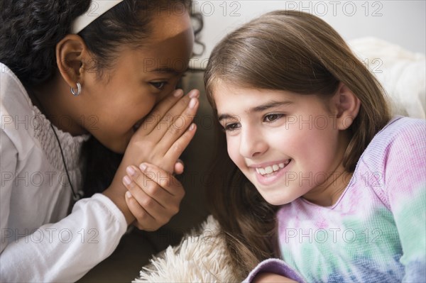 Smiling girls whispering on sofa