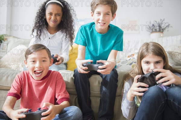 Children playing video games on sofa