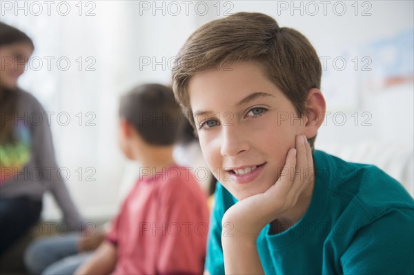 Smiling boy resting chin in hand in living room