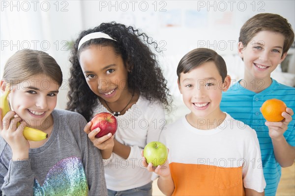 Smiling children playing with healthy fruit
