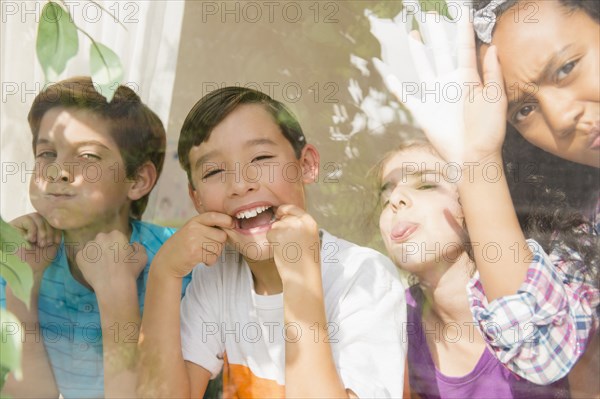 Children making faces behind window