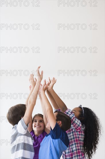 Smiling children raising hands in center