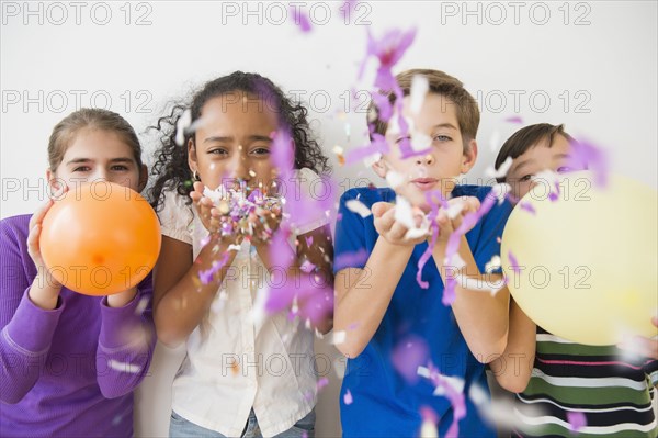 Children blowing party confetti and balloons