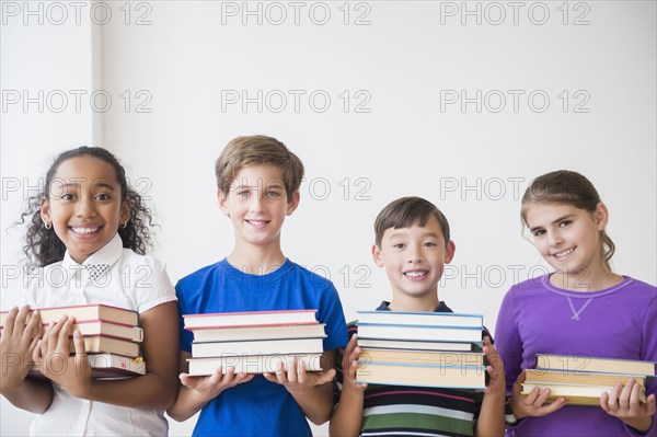 Students holding stacks of books