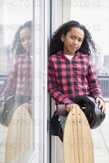 Mixed race girl standing with skateboard outdoors