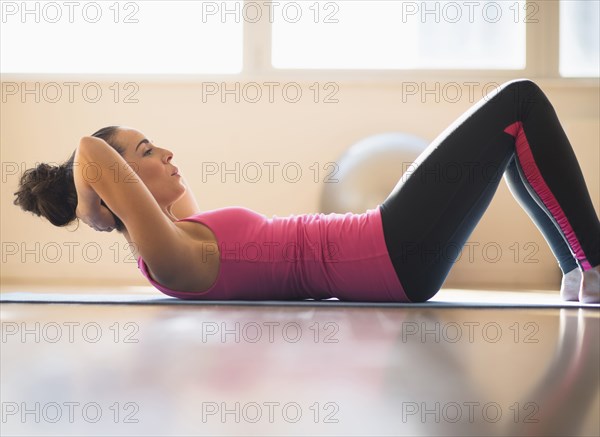 Close up of Hispanic woman doing sit-ups in gym